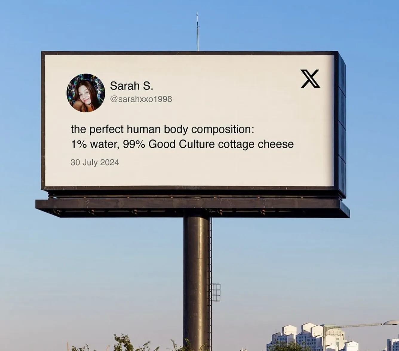 A billboard displaying a tweet on a white background set against urban landscape.