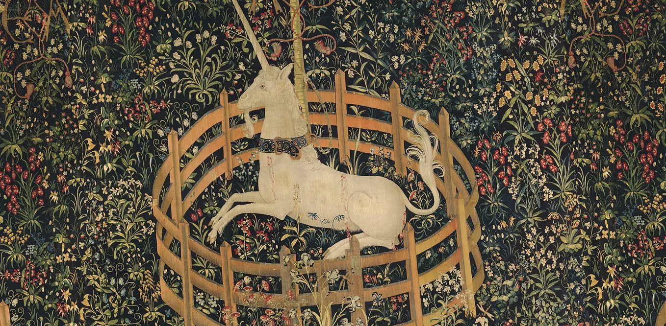 Medieval tapestry of a unicorn kneeling inside a very small fence, surrounded by elaborate flowers and plants.
