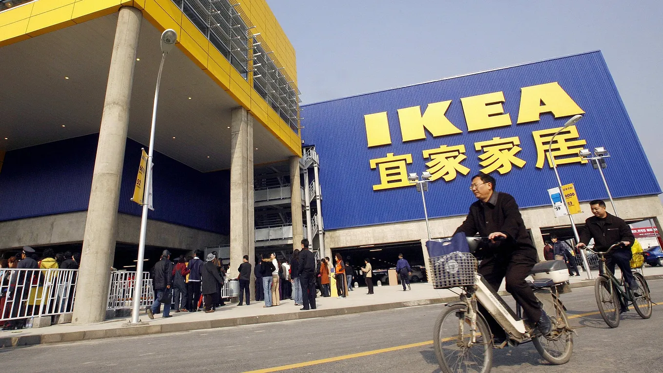 A man biking in front of a large IKEA store in Shanghai