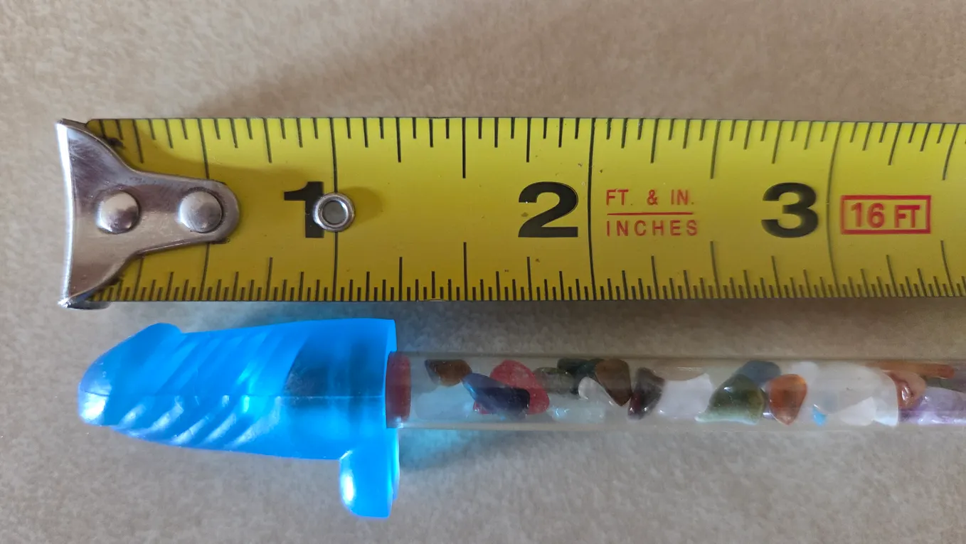 A pencil with a penis pencil-topper next to a measuring tape