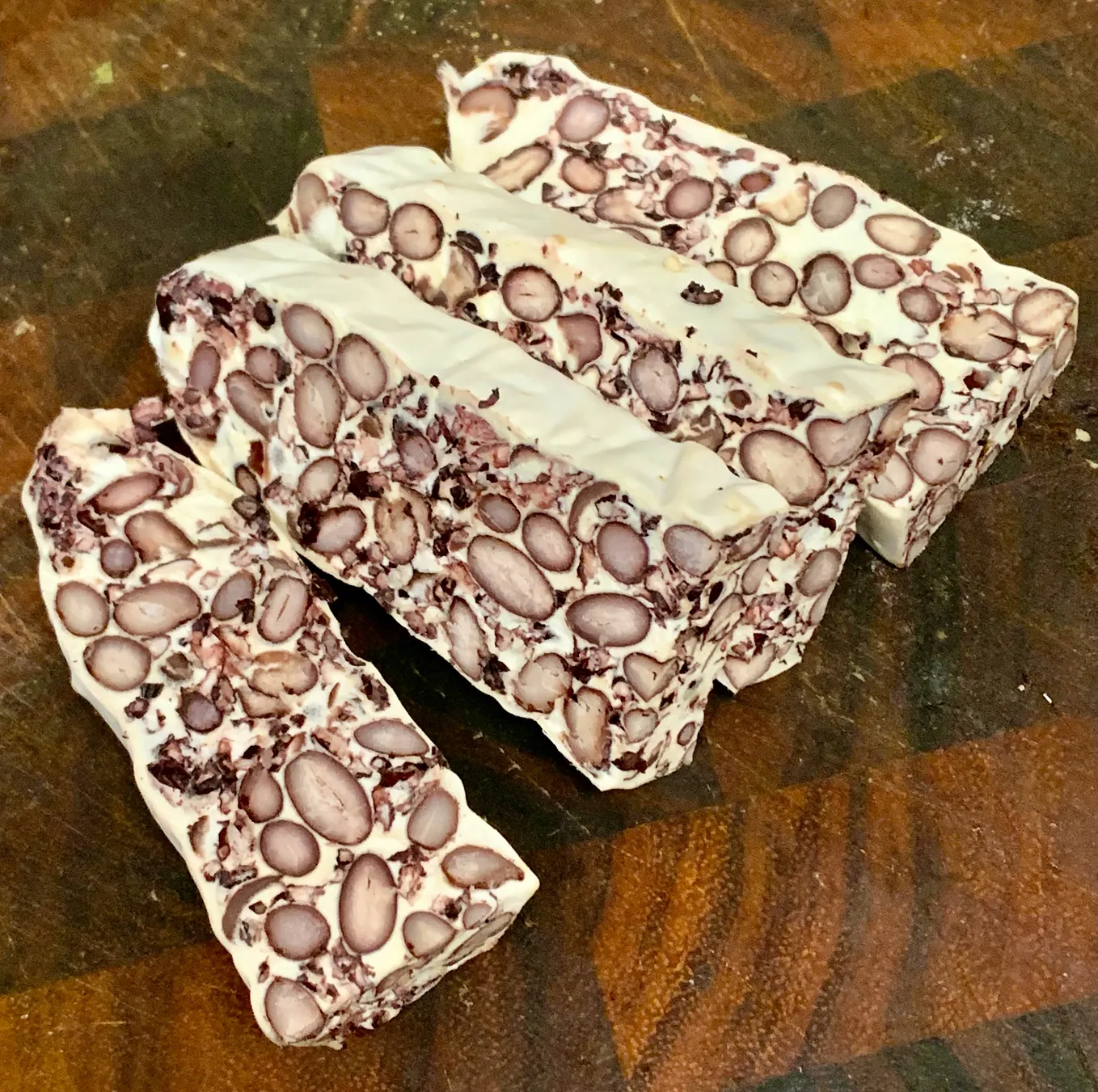 Four slices of tempeh showing the dark beans and black rice embedded in the white matrix of the tempeh fungus mycelium. The top of each slice is cover in the white mycelium.