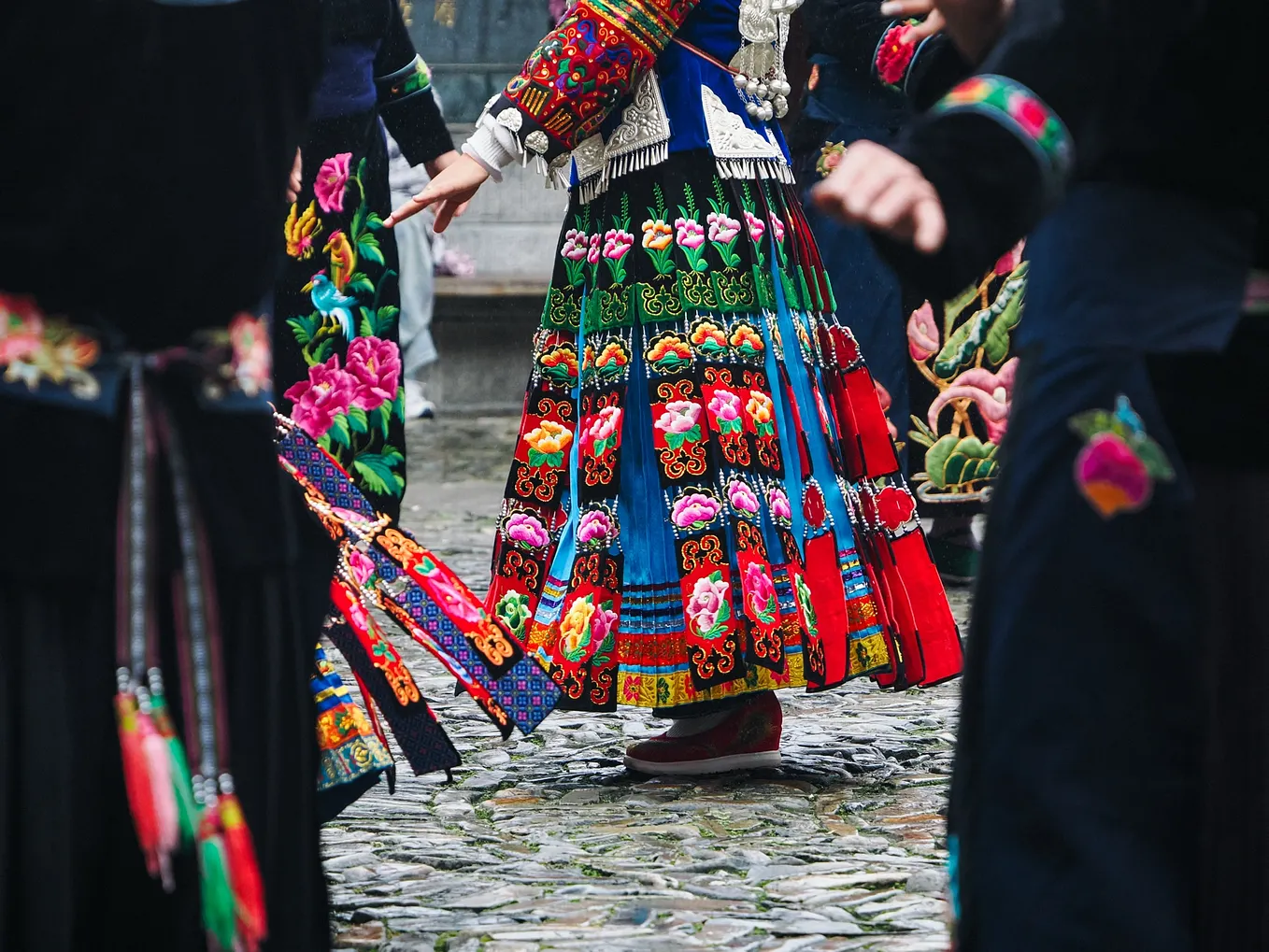 Focusing on a multicoloured embroidered skirt through the crowd of dancers