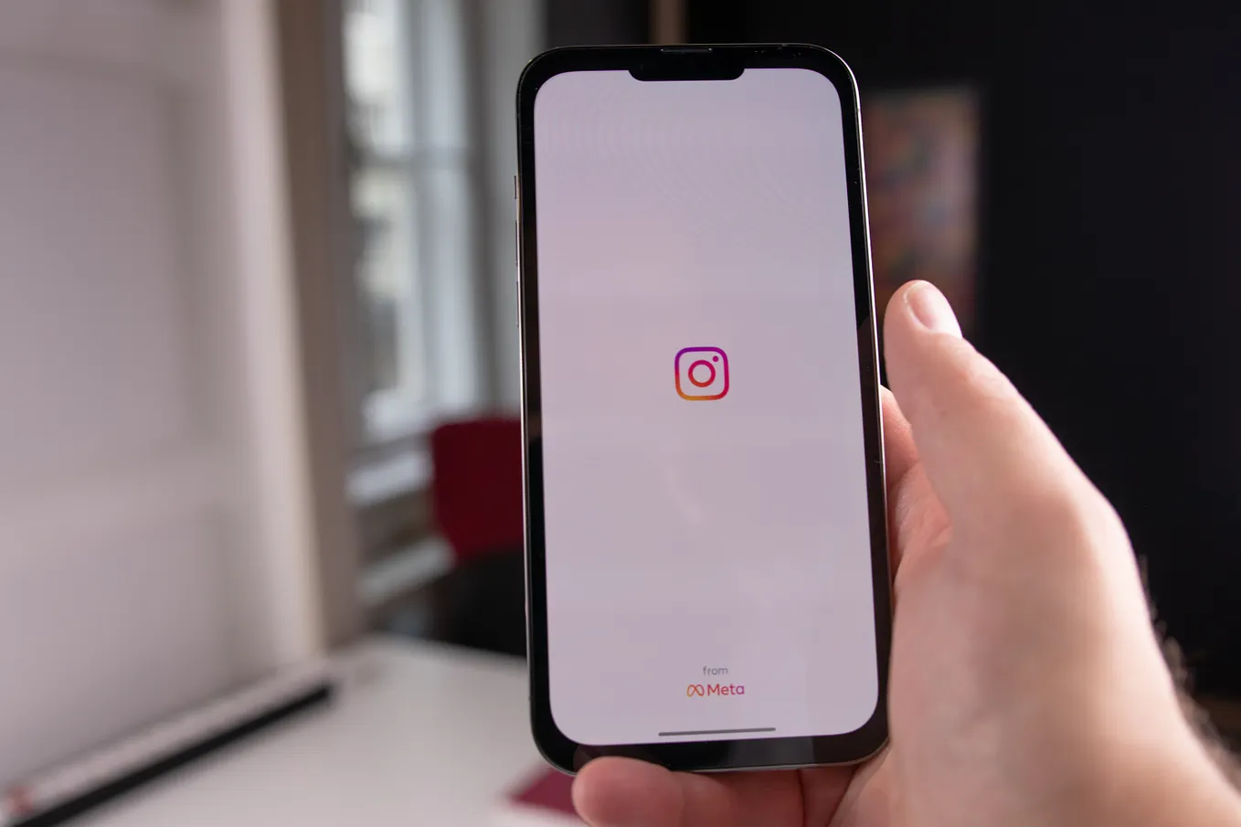 Image of a person holding an iPhone and opening Instagram app.