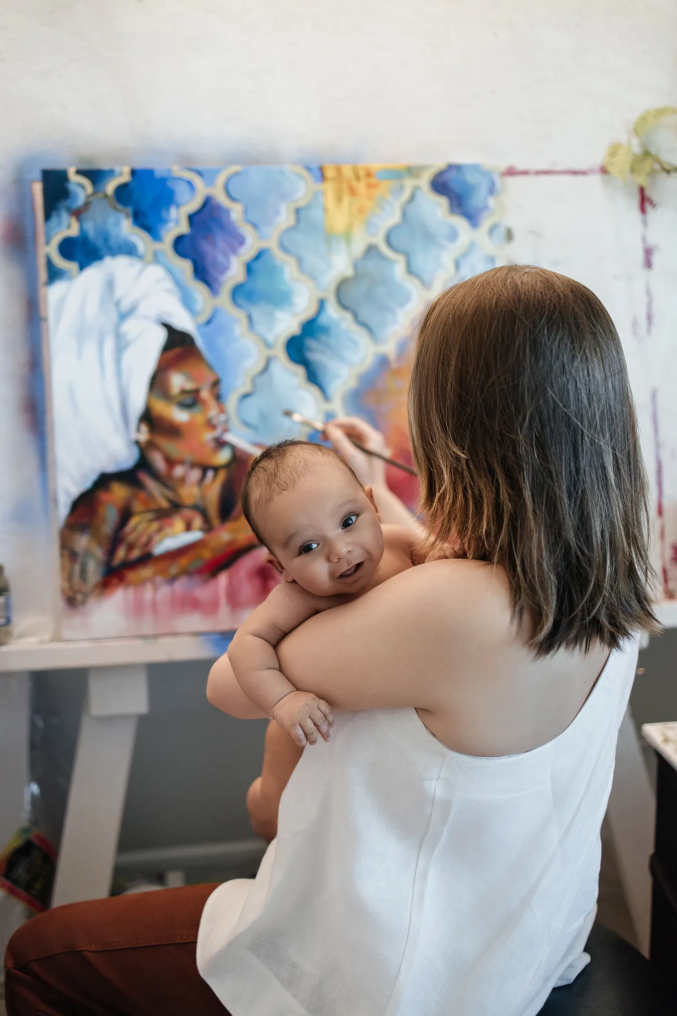 mother holding baby while painting a picture