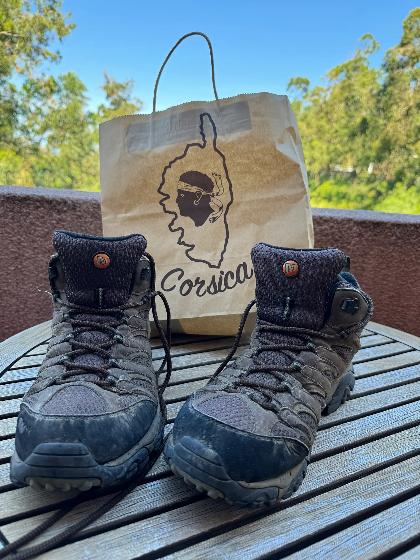 Hiking boots against shopping bag with Corsica logo