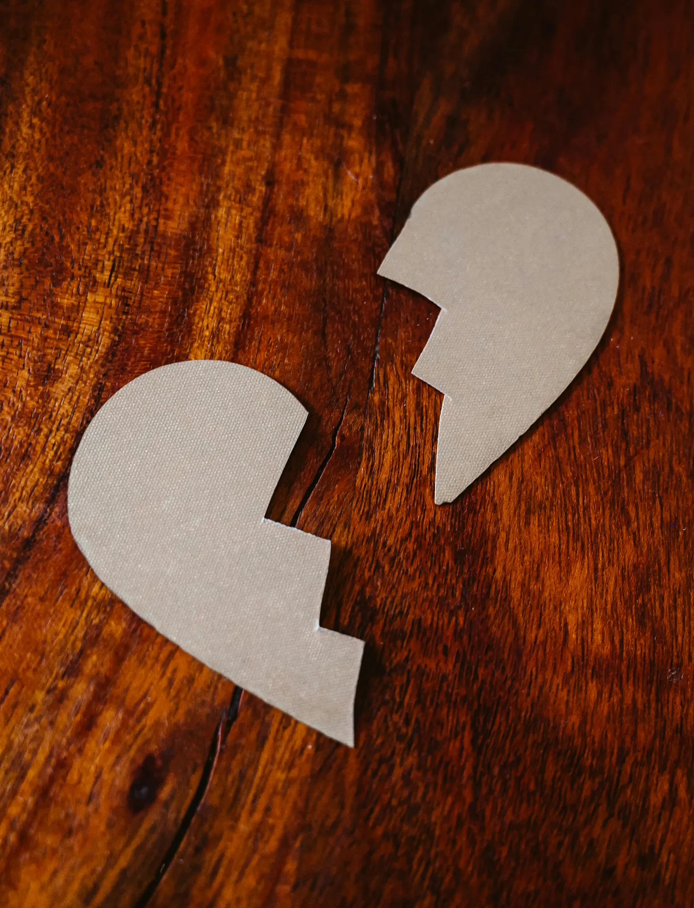 Image of a broken cardboard heart on a wooden surface