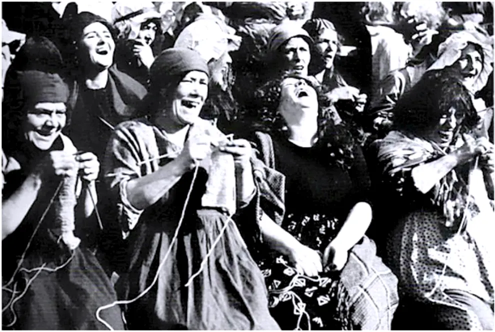 Black and white photo of women in peasant clothes knitting and laughing wildly
