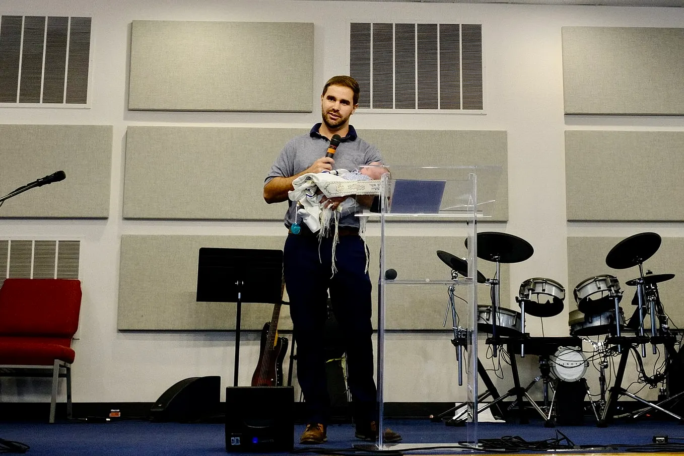 A man holds a baby in one arm and a microphone in the next