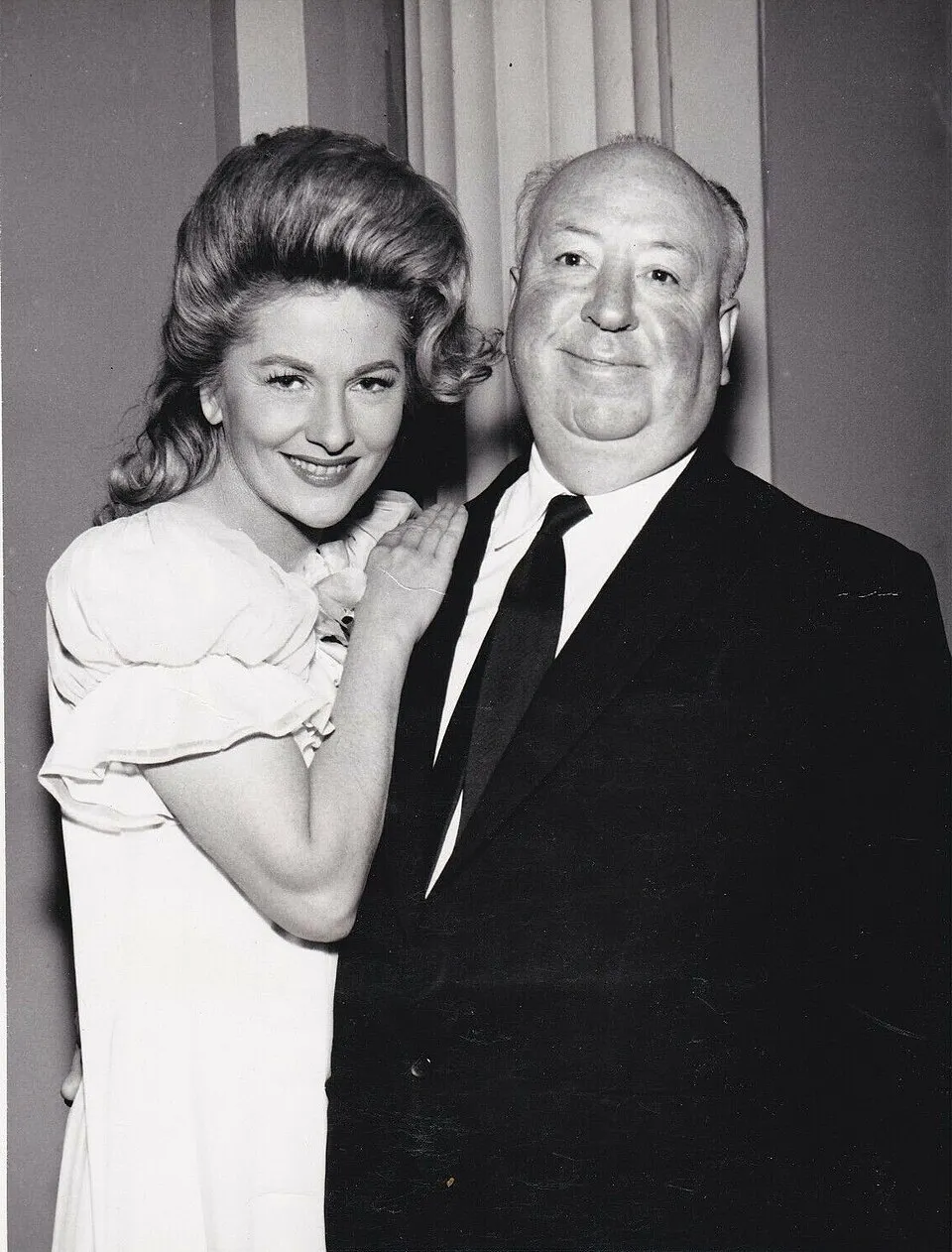 Black and white photo of Fontaine and Hitchcock standing close together in 1963.