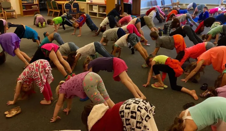 Children doing mountain pose with the feet and hands on the ground and their bodies forming a mountain shape in the air.