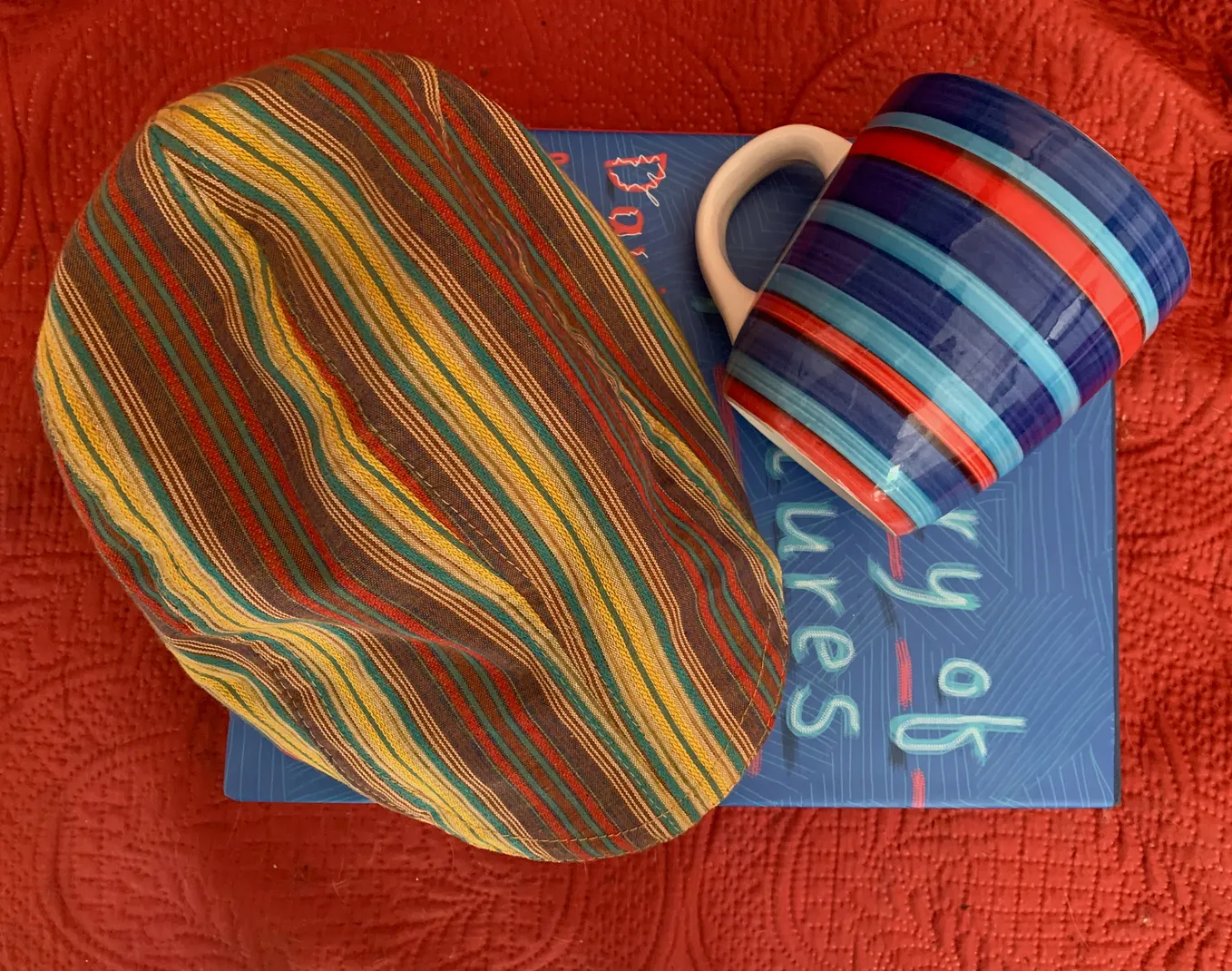 a striped cap and a striped mug on a blue book