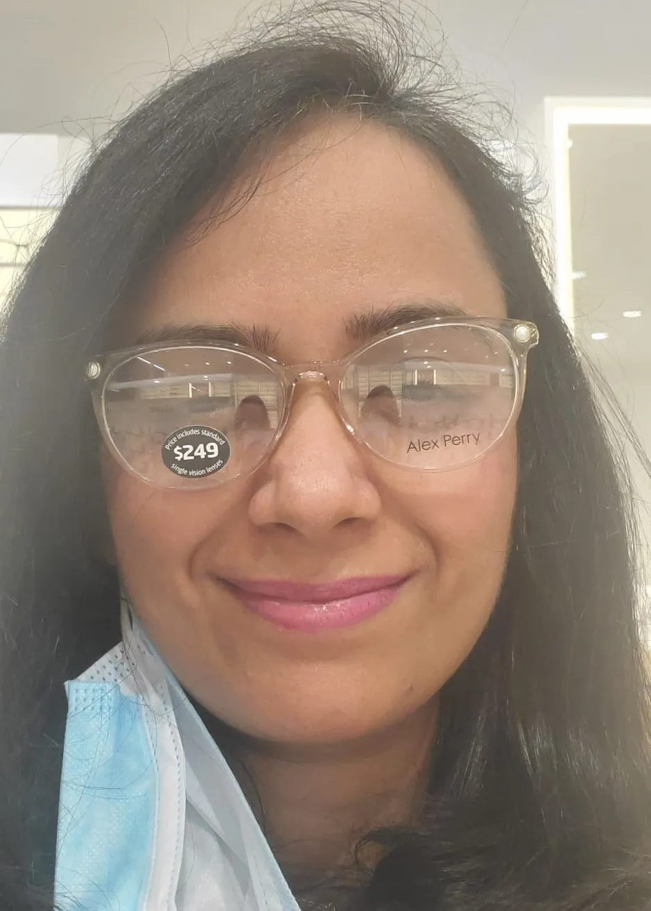 A close-up of a woman’s face trying a pair of reading glasses