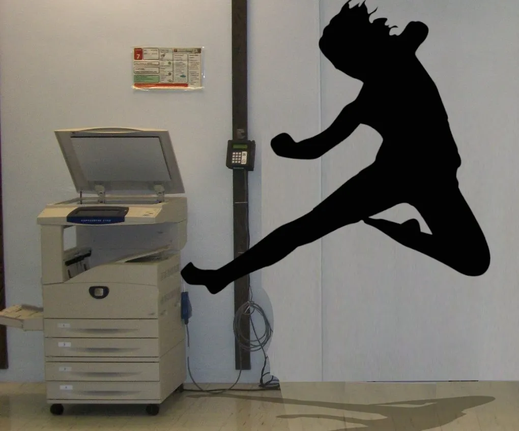 A photocopier in an office copy room; a silhouetted figure is dealing a flying kick to it. Image: Temple University Libraries (modified) https://www.flickr.com/photos/tulpics/4882641645/ CC BY 2.0: https://creativecommons.org/licenses/by/2.0/