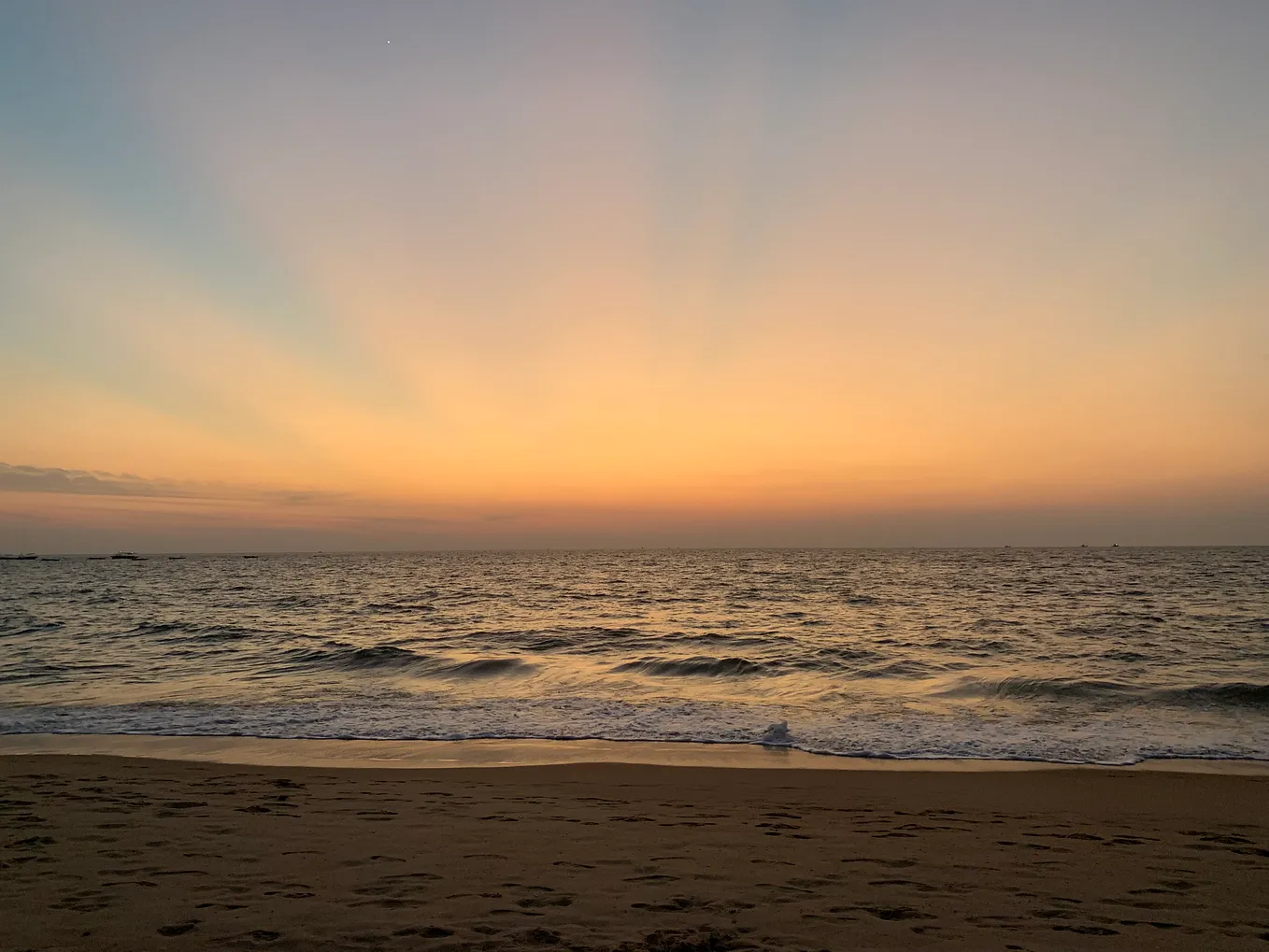 a sunset on the beach, taken from the coast with brilliant rays of sunlight visible