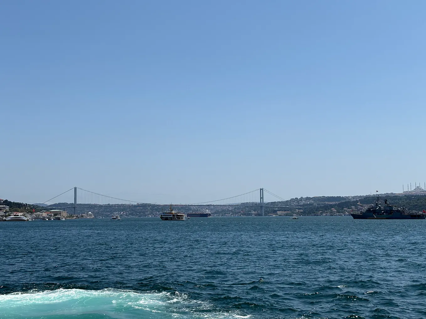 The photo shows the Bosphorus Strait and the Bosphorus Bridge. There are also ships sailing on the blue sea.
