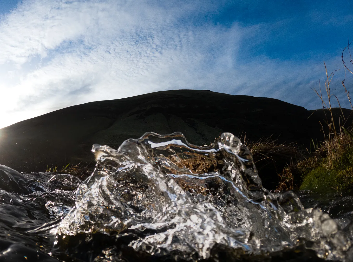 A close-up perspective of water turbulence from a river with mountains in the background.