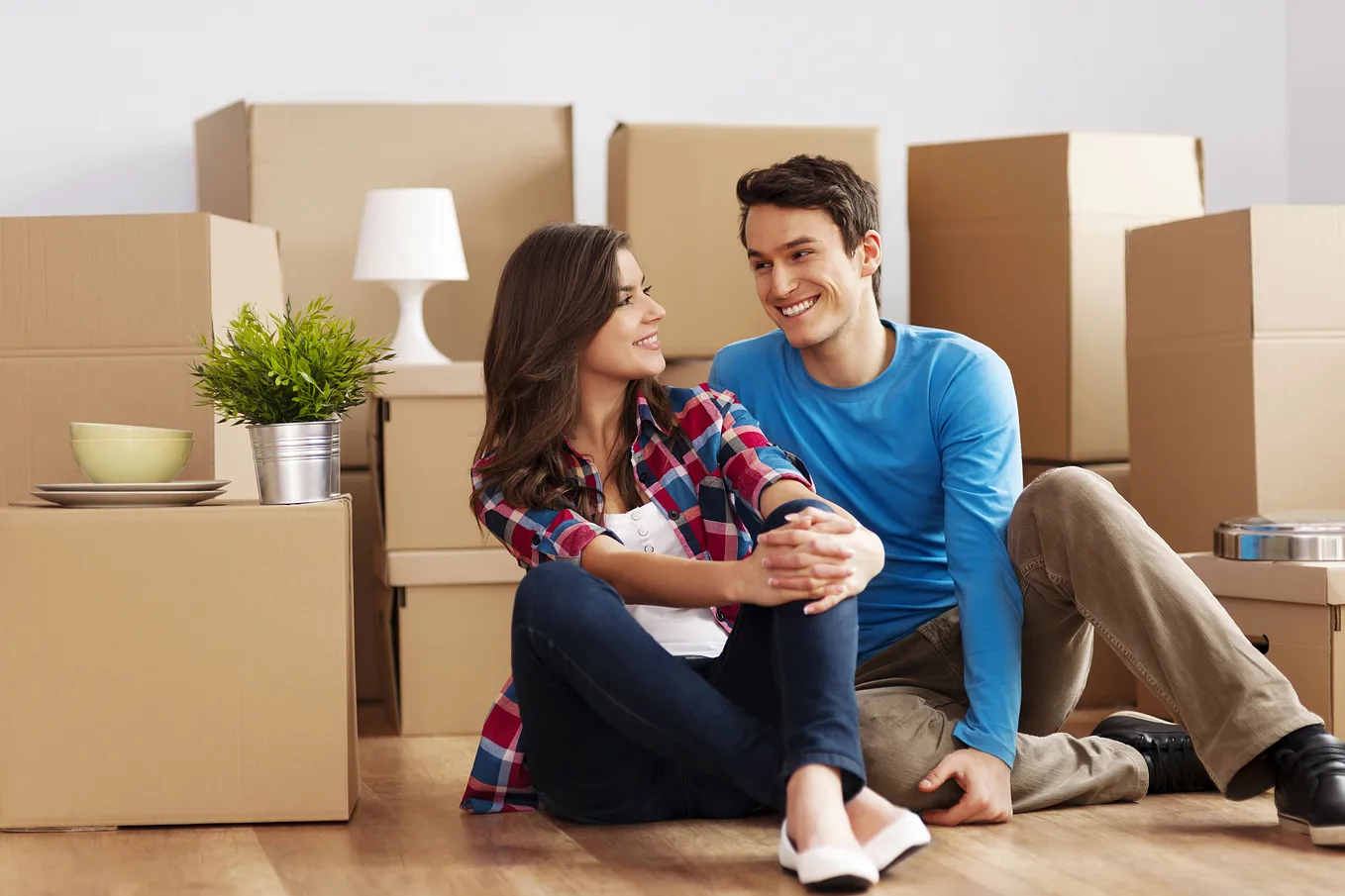 A man and a woman sitting on the floor surrounded by boxes