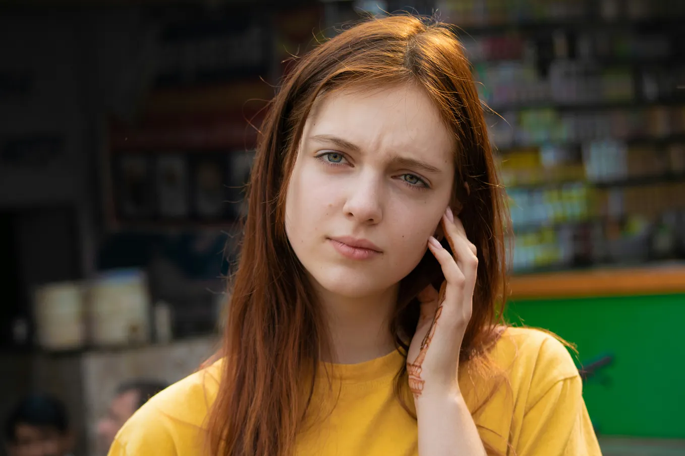 Red-haired woman in yellow shirt looking confused