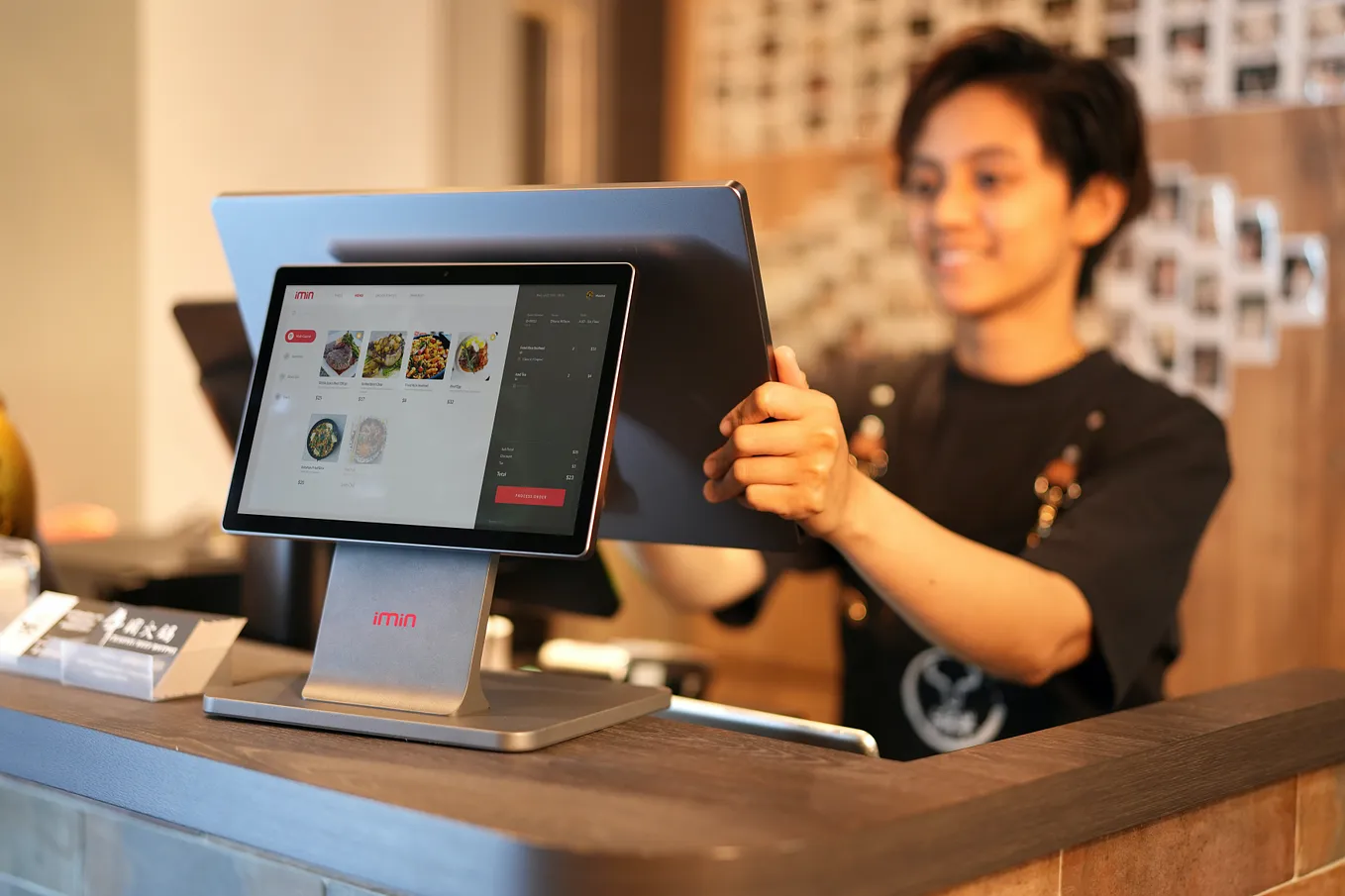 Woman in Black Crew Neck T-shirt Holding Black Tablet Computer and handling digital menu for restaurant orders