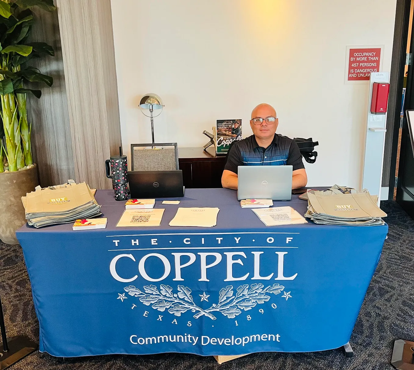Luay Rahil sitting behind a table while hosting a job fair at the city of Coppell.