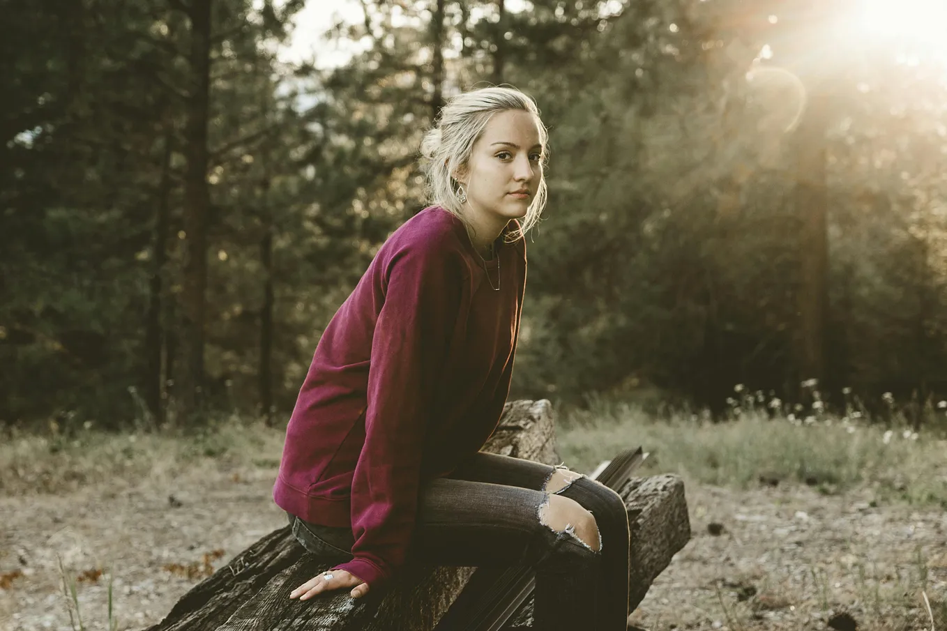 A woman sitting on a log in the forest