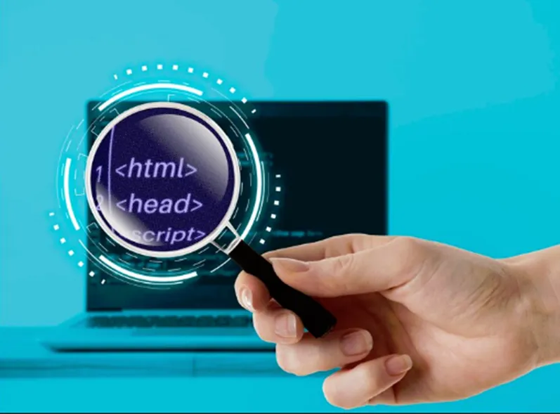 A photo of a hand holding a magnifying glass in front of a laptop screen displaying computer code.