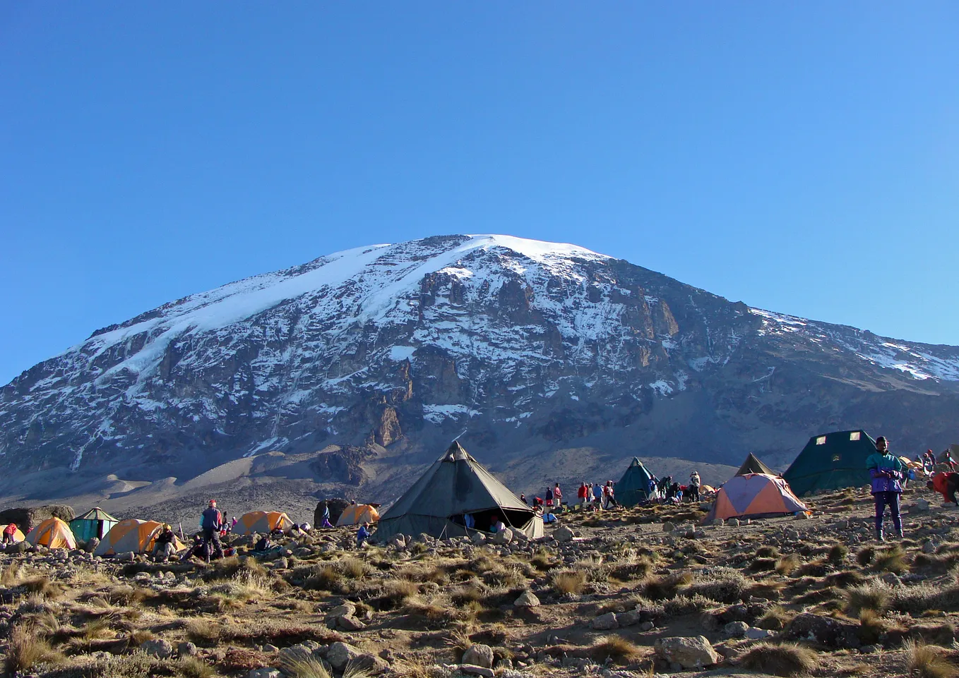 Tents set up at the base of a snowy mountain top.