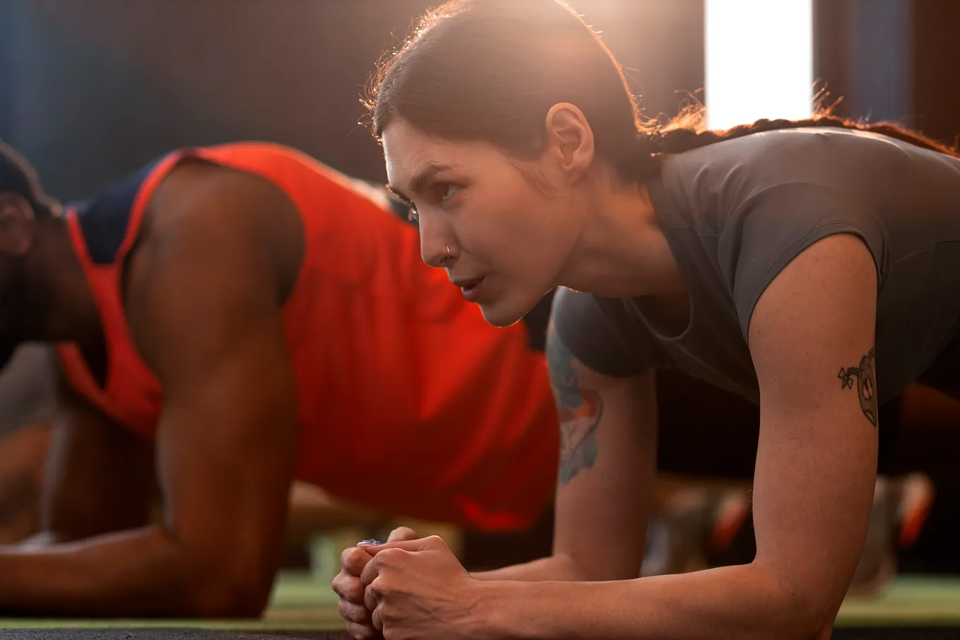 A woman struggling to hold a plank position during an exercise class.