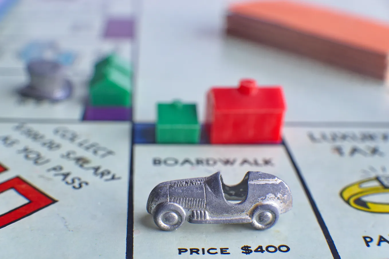 close up of a Monopoly board with a car on Boardwalk and houses and hotels around