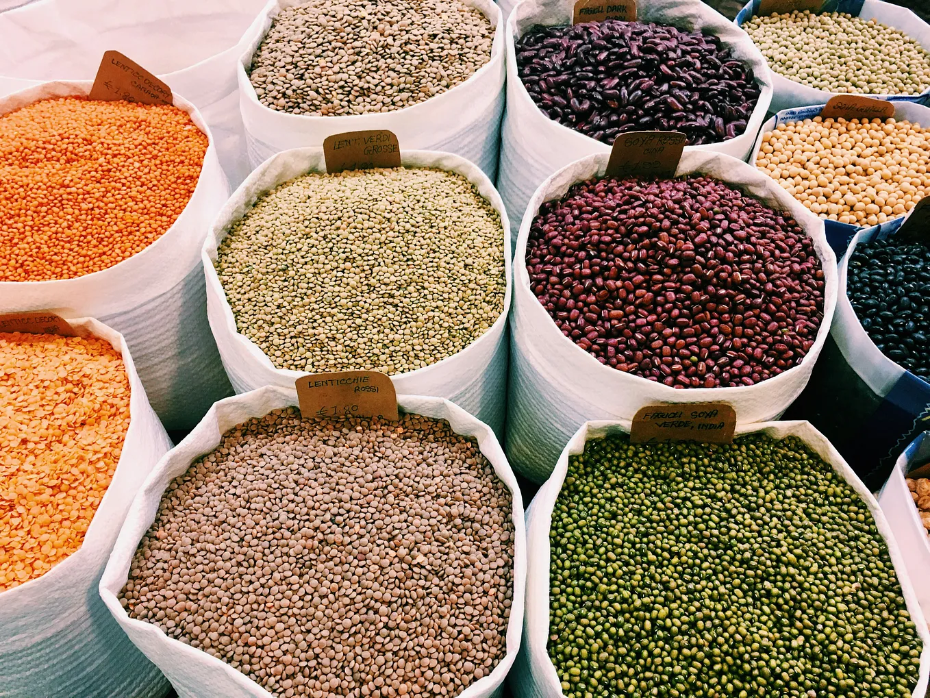 Many large containers of different-colored beans.