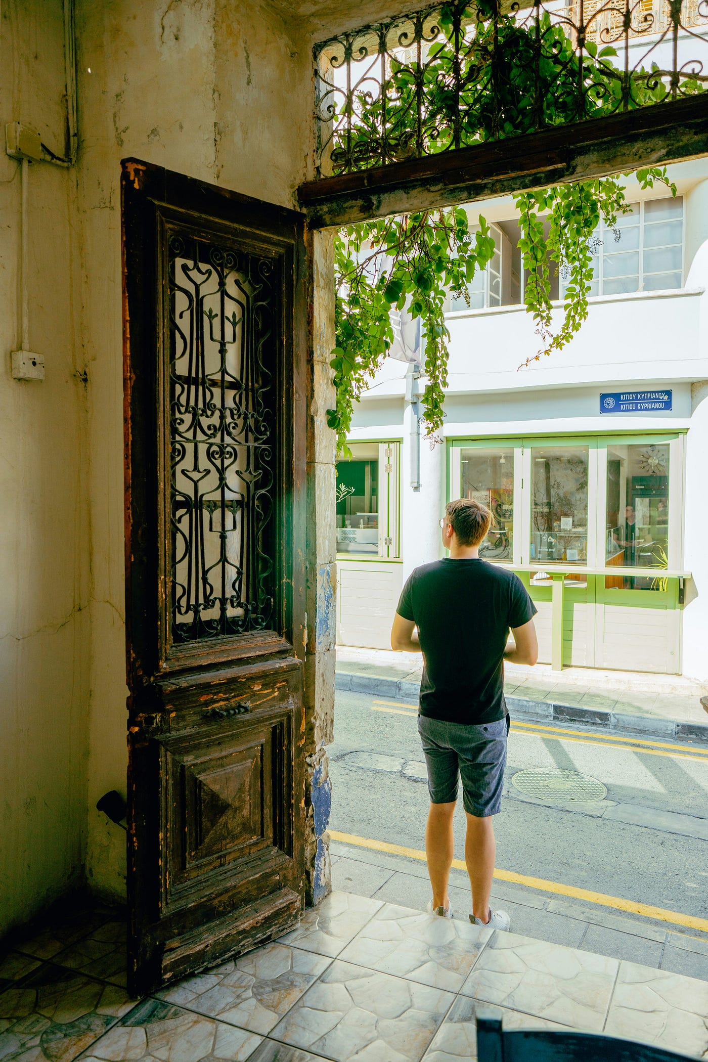 문간에 서서 집 밖을 바라보는 남자.