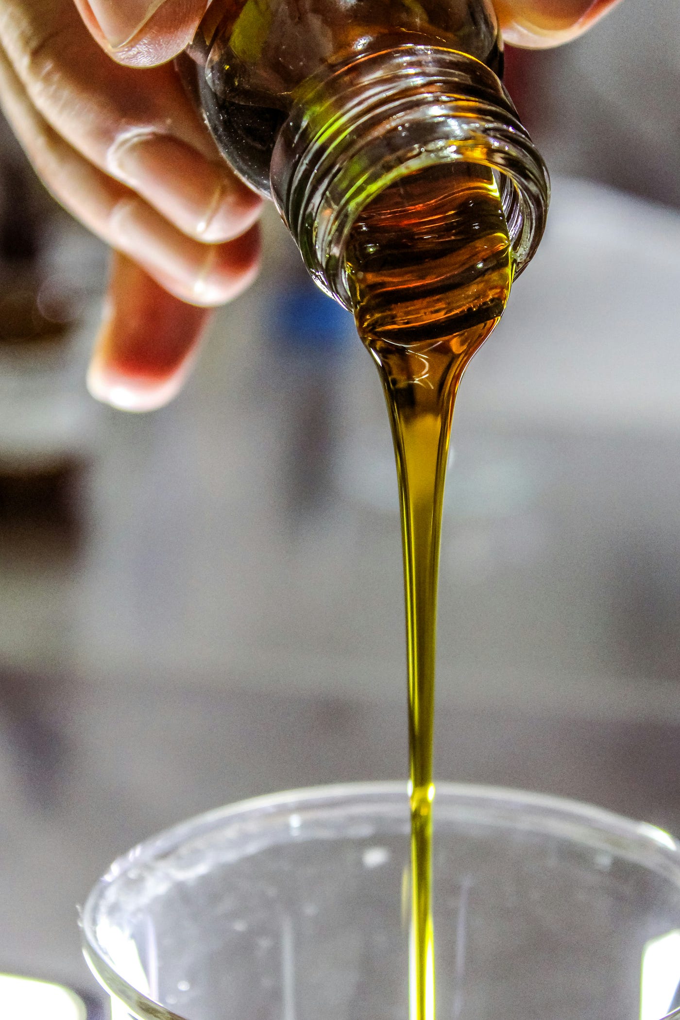 A person pours olive oil into a cup. The Atlantic diet includes olive oil.