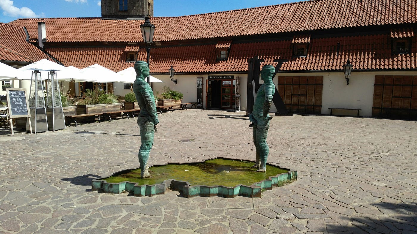 Photo by Olesia Libra on Unsplash — Piss - art installation by David Cerny in front of Franz Kafka museum in Prague. Two mechanical men urinating on a map of the Czech Republic. You can send a text message and the two men will spell it with their penises.