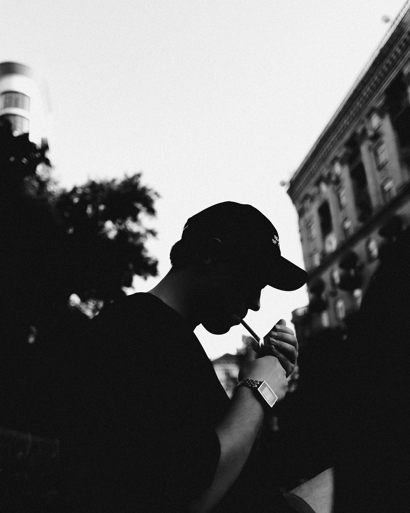 A black and white image of a man in profile, smoking a cigarette.