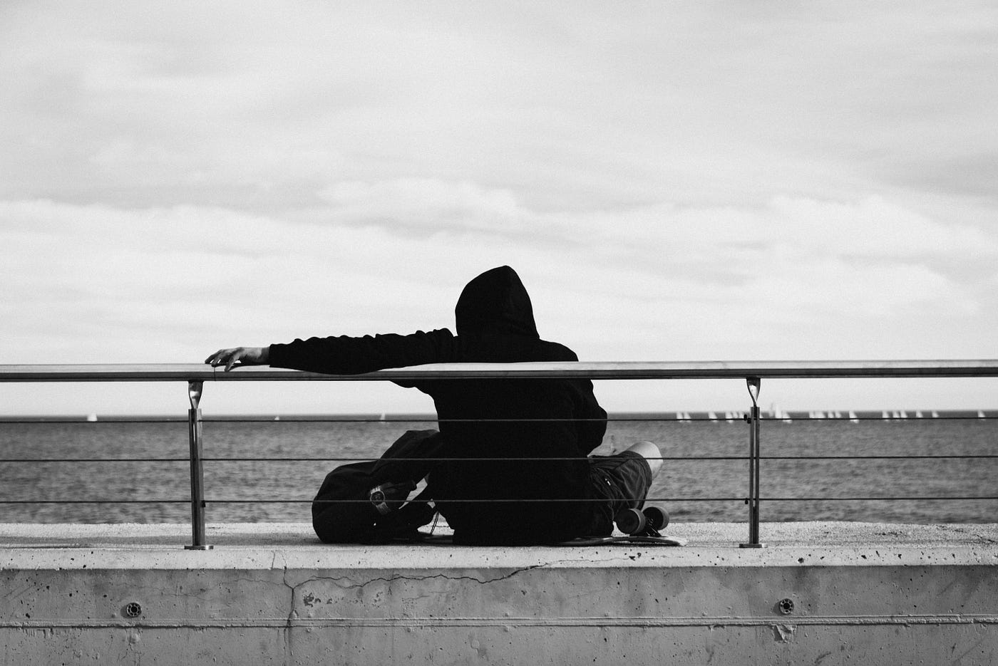 한 사람이 땅바닥에 홀로 앉아 생각에 잠겨 있다.