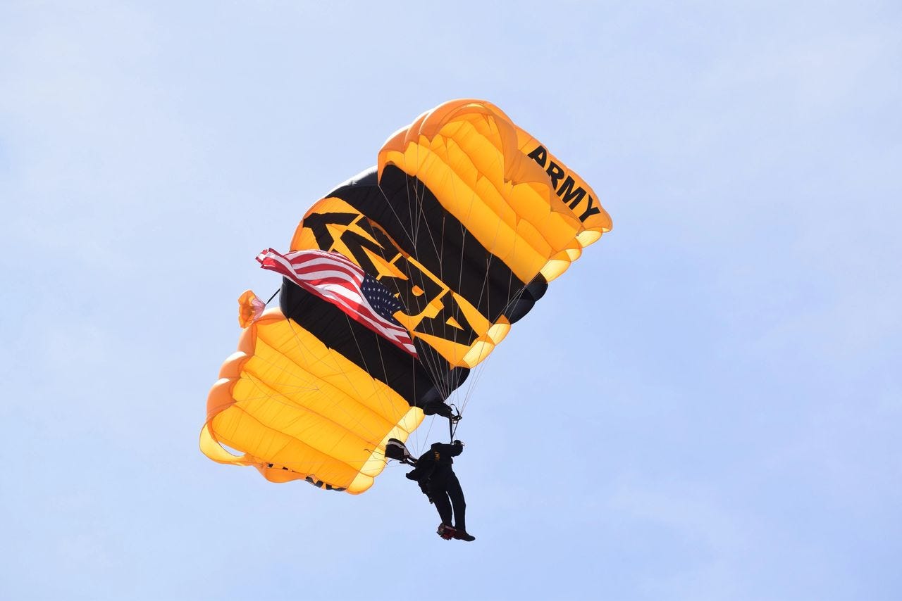 Mickey Markoff 2024 Air Sea Exec — photo of US army parachute jump in sky with yellow army parachute and american flag