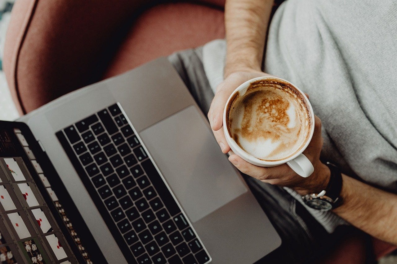 Relaxed workspace vibes: enjoying a latte while working on a laptop, perfect for setting intentions, reflecting on daily goals, or finding inspiration to tackle your morning routine with focus.
