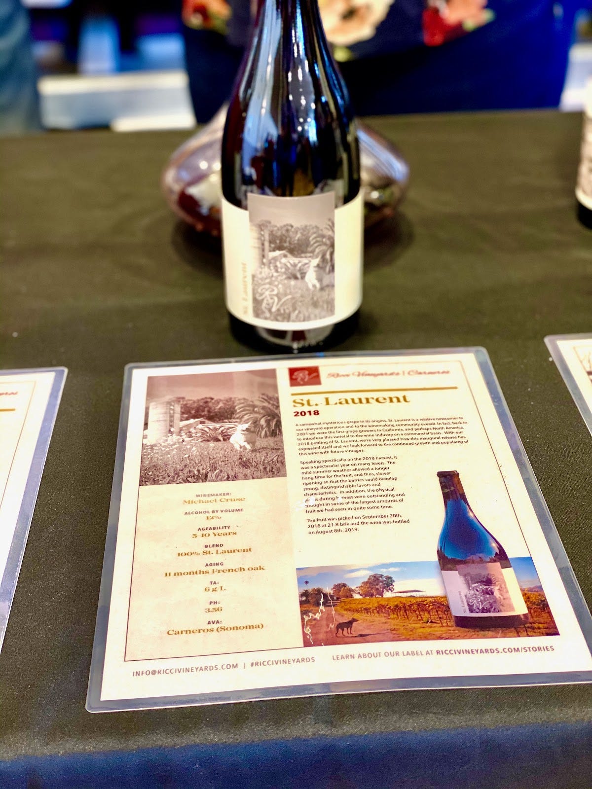 A piece of laminated paper with information about St. Laurent wine in front of a wine bottle.