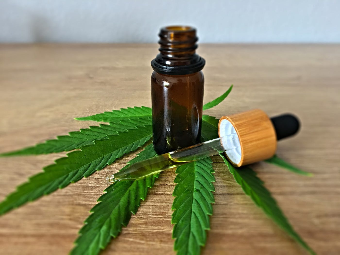 A bottle is placed on a cannabis leaf that contains Full Extract Cannabis Oil which is placed beside a dropper with cannabis oil in it.