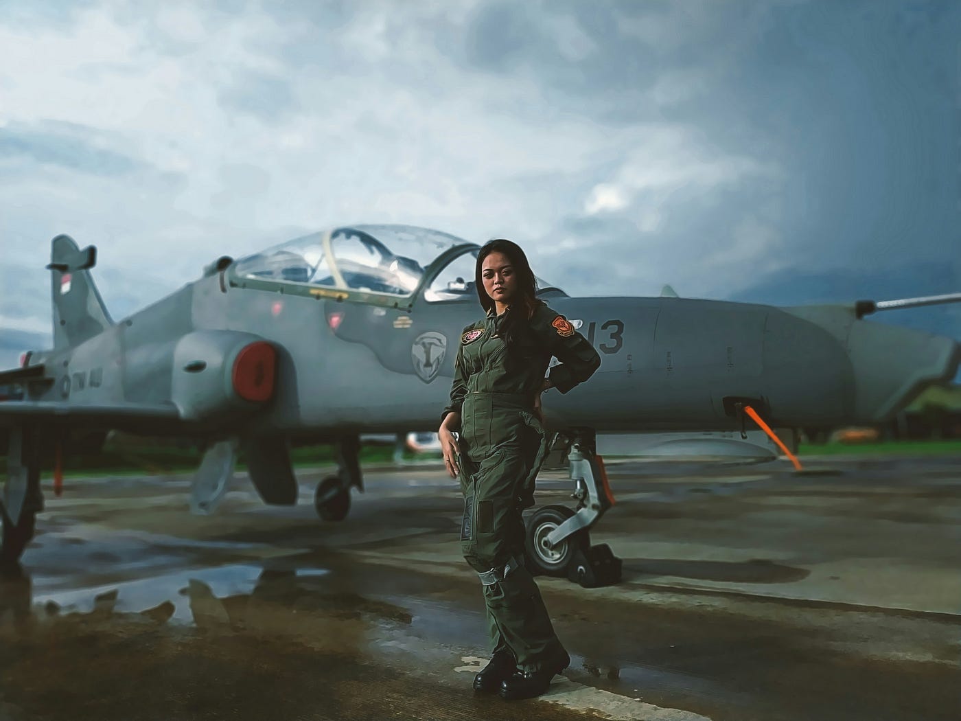 여성 조종사가 석양을 배경으로 활주로에서 전투기 옆에 서 있다.<BR>