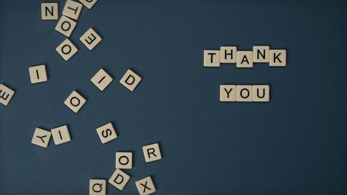 Mickey markoff air sea exec 2024 — photo of scrabble tiles strewn on table, selected few spelled out to say ‘thank you’ on blue background. Photo on mickey markoff 2024 article about net worth of gratitude