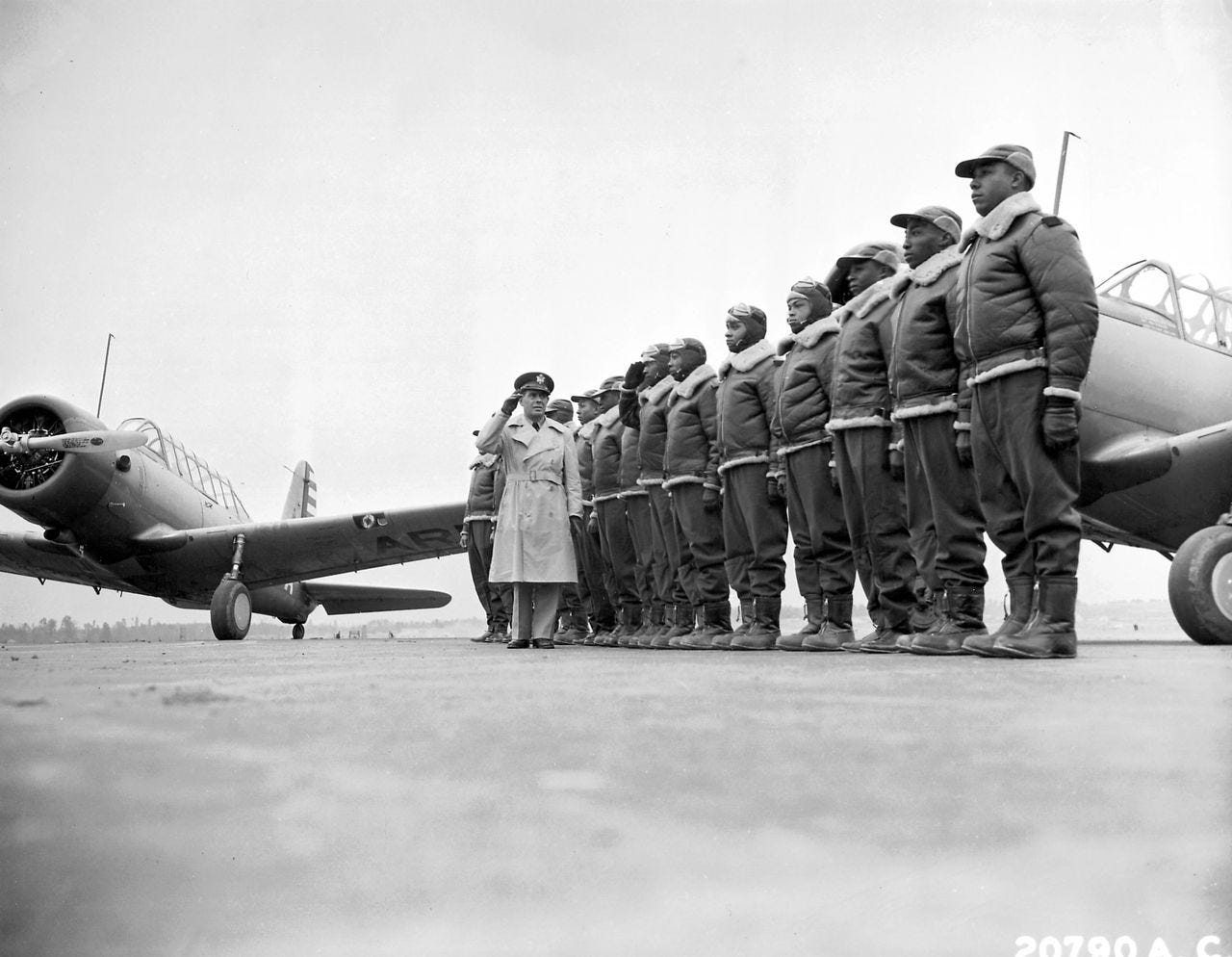 Mickey Markoff Air Sea Exec 2024 — black and white photo of Tuskegee Airmen in uniform in front of military aircraft. Men wearing bomber jackets and hats with other person wearing trench coat and hat. Posted on 2024 Mickey Markoff article on black history month in aviation