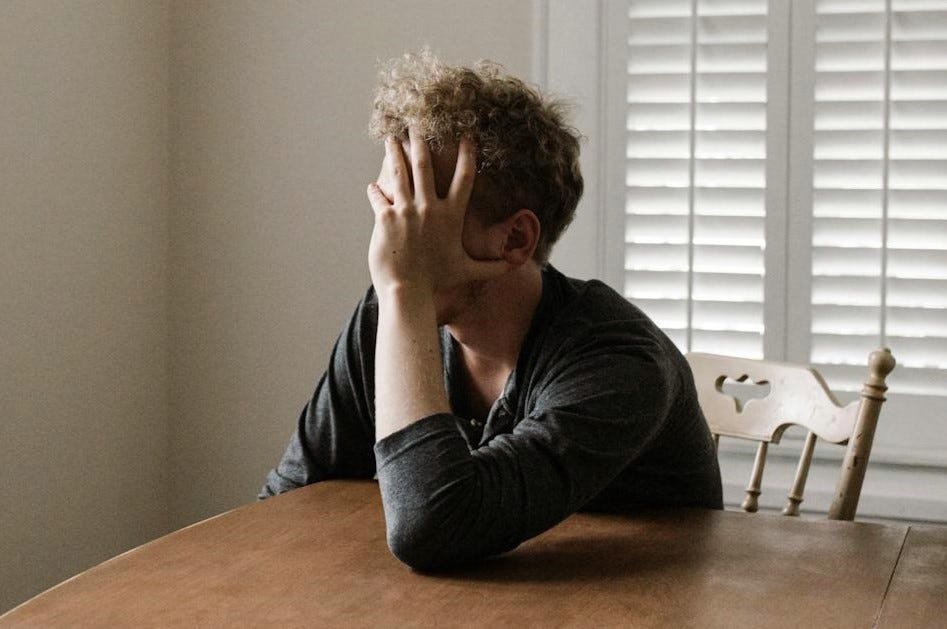 머리에 손을 얹고 테이블에 기대어 있는 남자