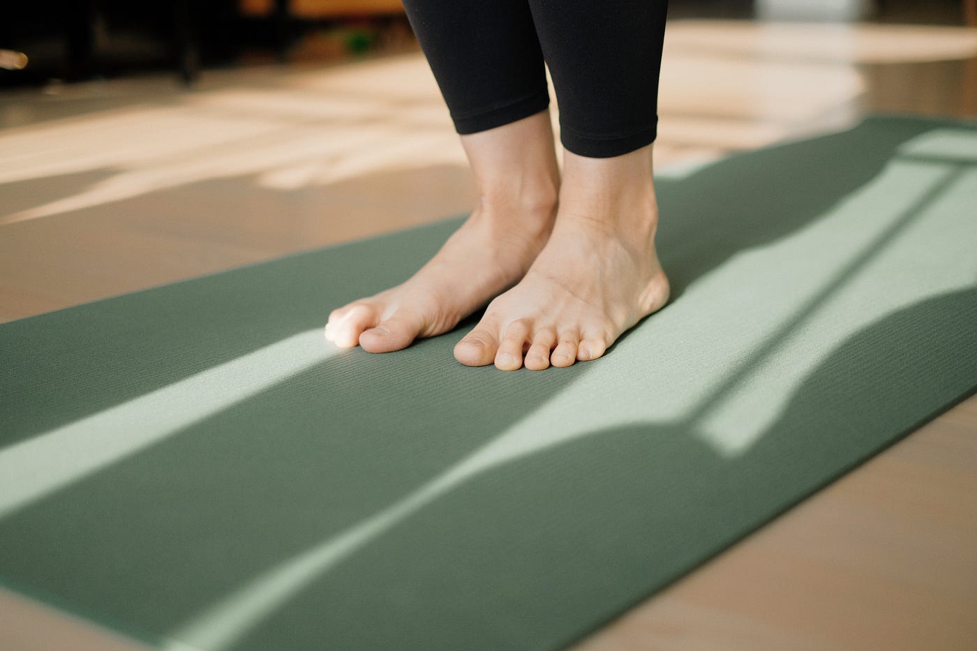 We see two feet on a yoga mat. Yoga or pilates can be excellent tools to enhance balance.