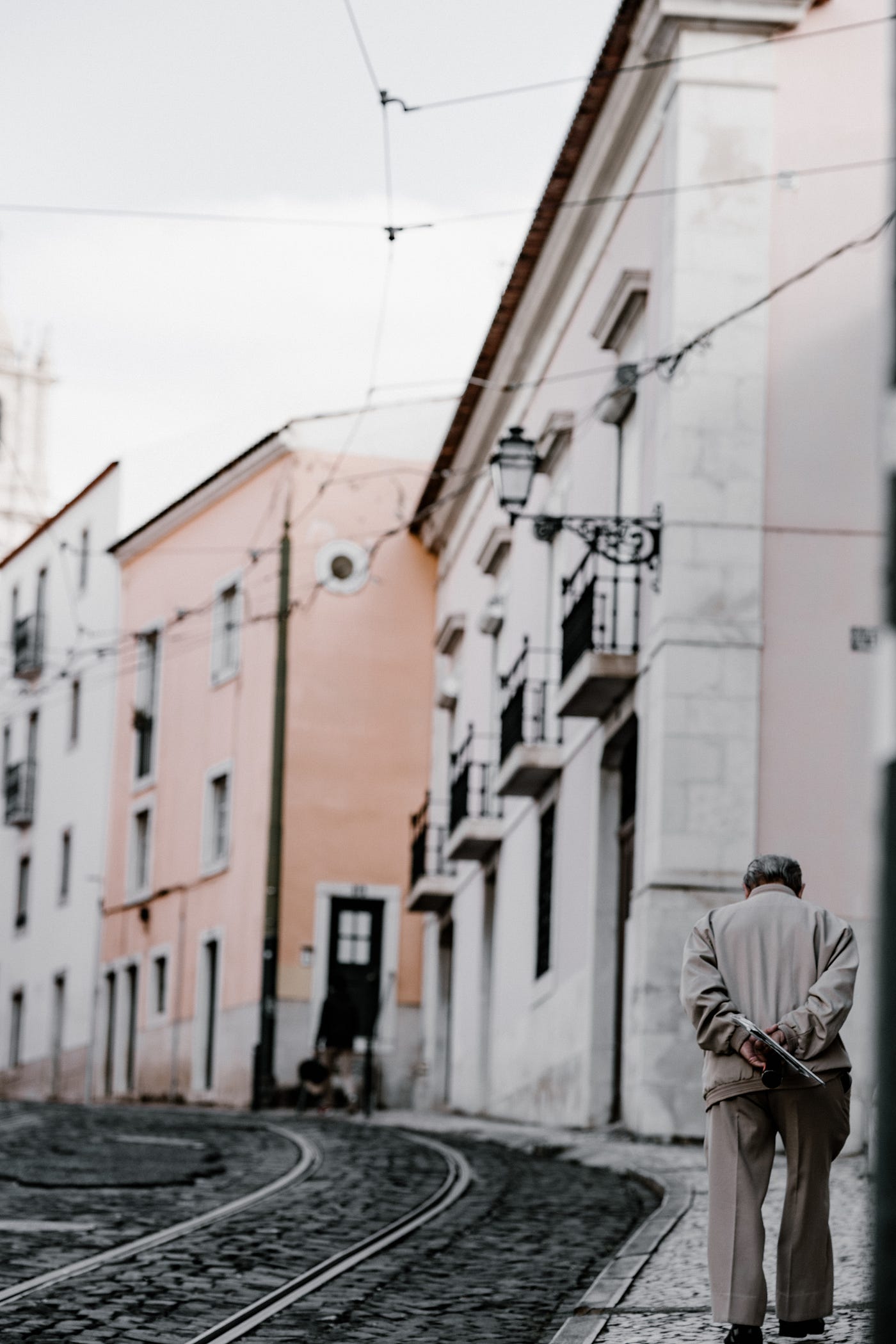 An older man walks in an old town in Europe, with streetcar  tracks running down the middle of the road. Building muscle strength can alleviate joint stress, promote proper alignment, and prevent further damage. Strengthening exercises, such as resistance training and weight-bearing activities, can be tailored to individual needs and abilities, aiding the fight against arthritis.