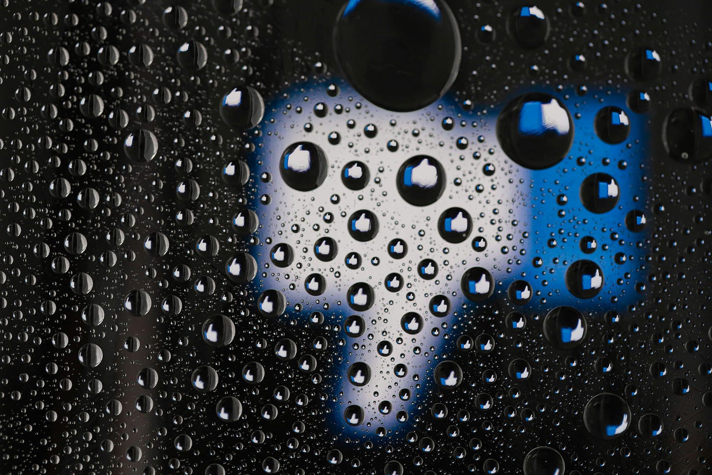 A thumbs down is seen behind a rain streaked glass.