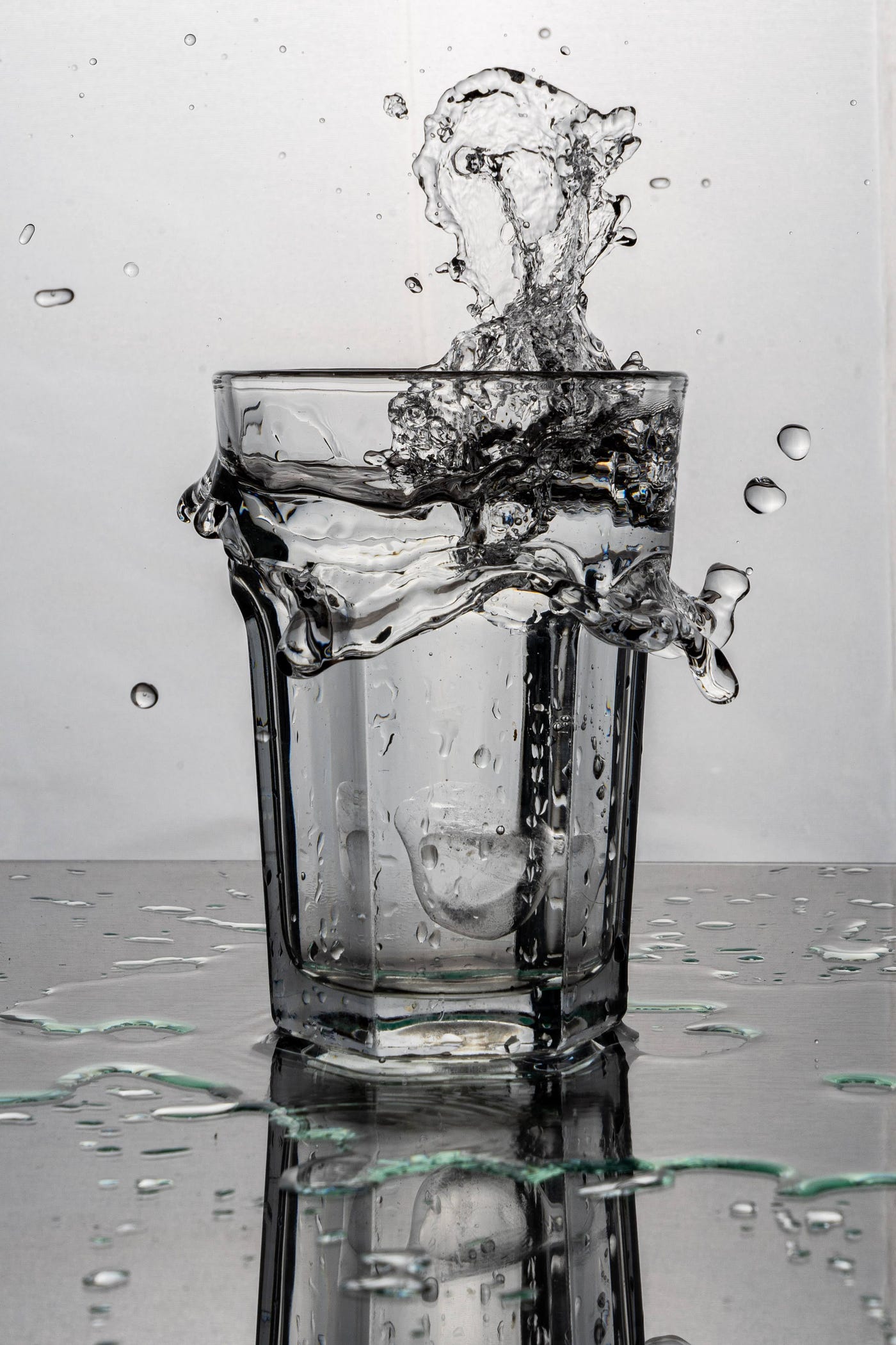 A black and white image of a glass of water splashing upward. To counteract the dehydrating effects of alcohol, alternating between sips of water and wine can help maintain hydration levels and reduce the risk of headaches. Try drinking a full glass of water before drinking wine.