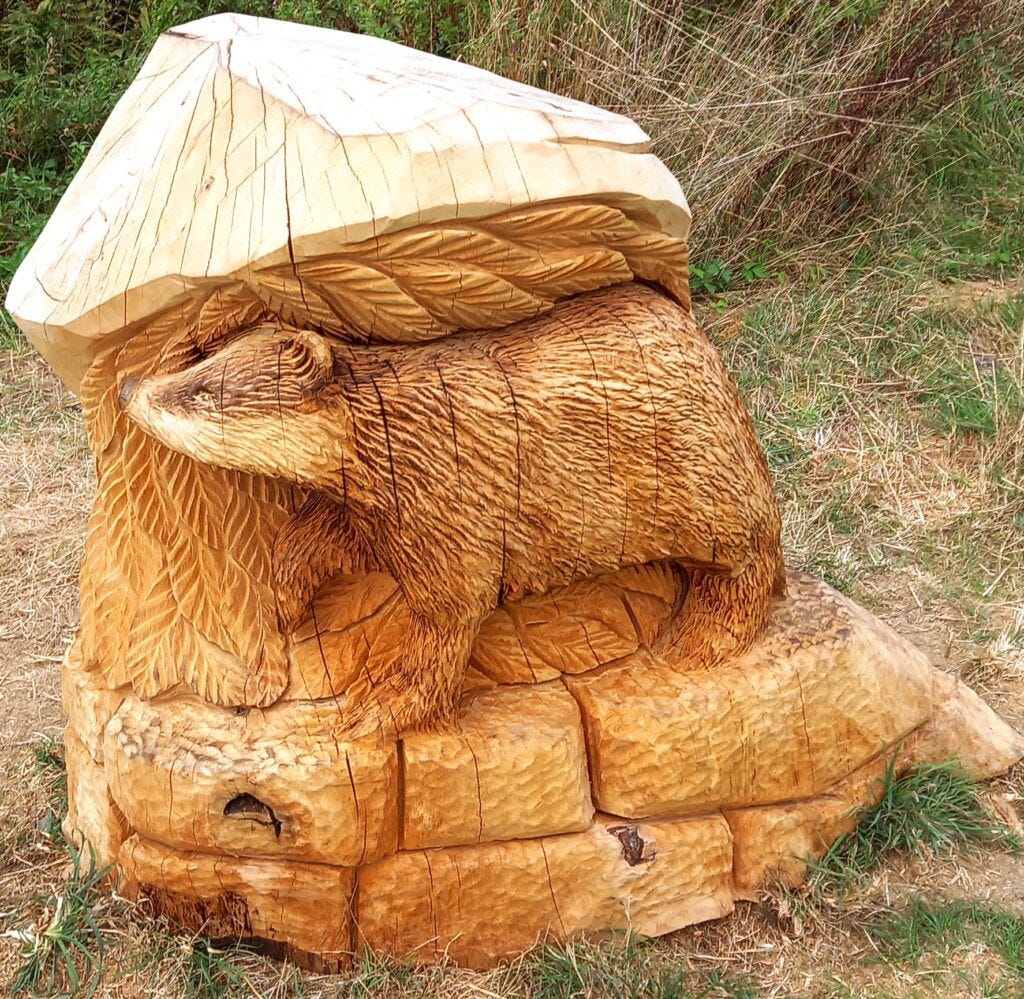 Image of carved badger from tree trunk on circle of carved bricks, with interwoven carved leaves background, to illustrate post