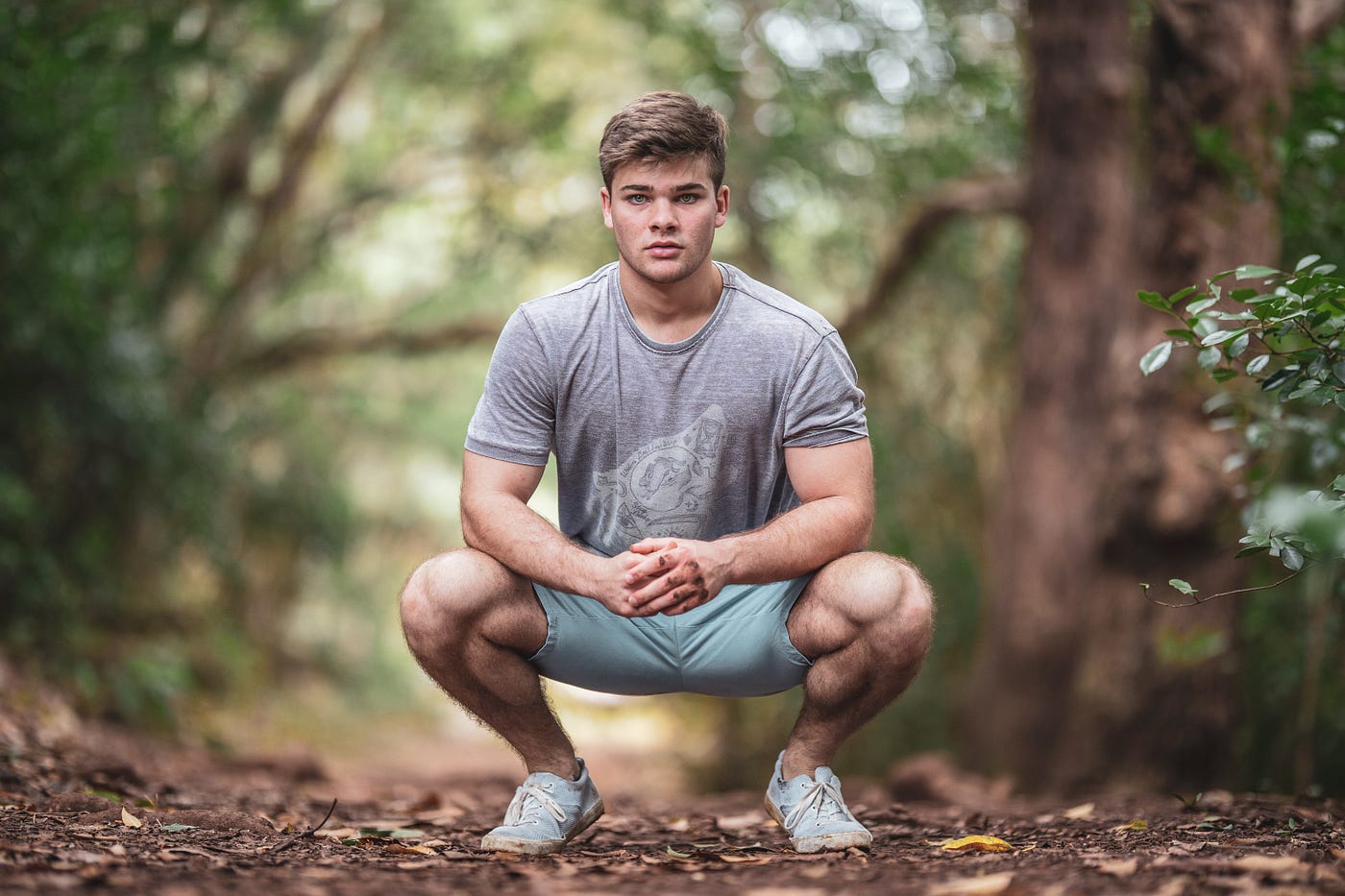 A young man faces us as he performs a bodyweight squat. Balance involves a complex interplay of sensory information from your eyes, ears, and muscles. This teamwork ensures you can adjust your position and distribute your weight accordingly, preventing those unexpected tumbles.