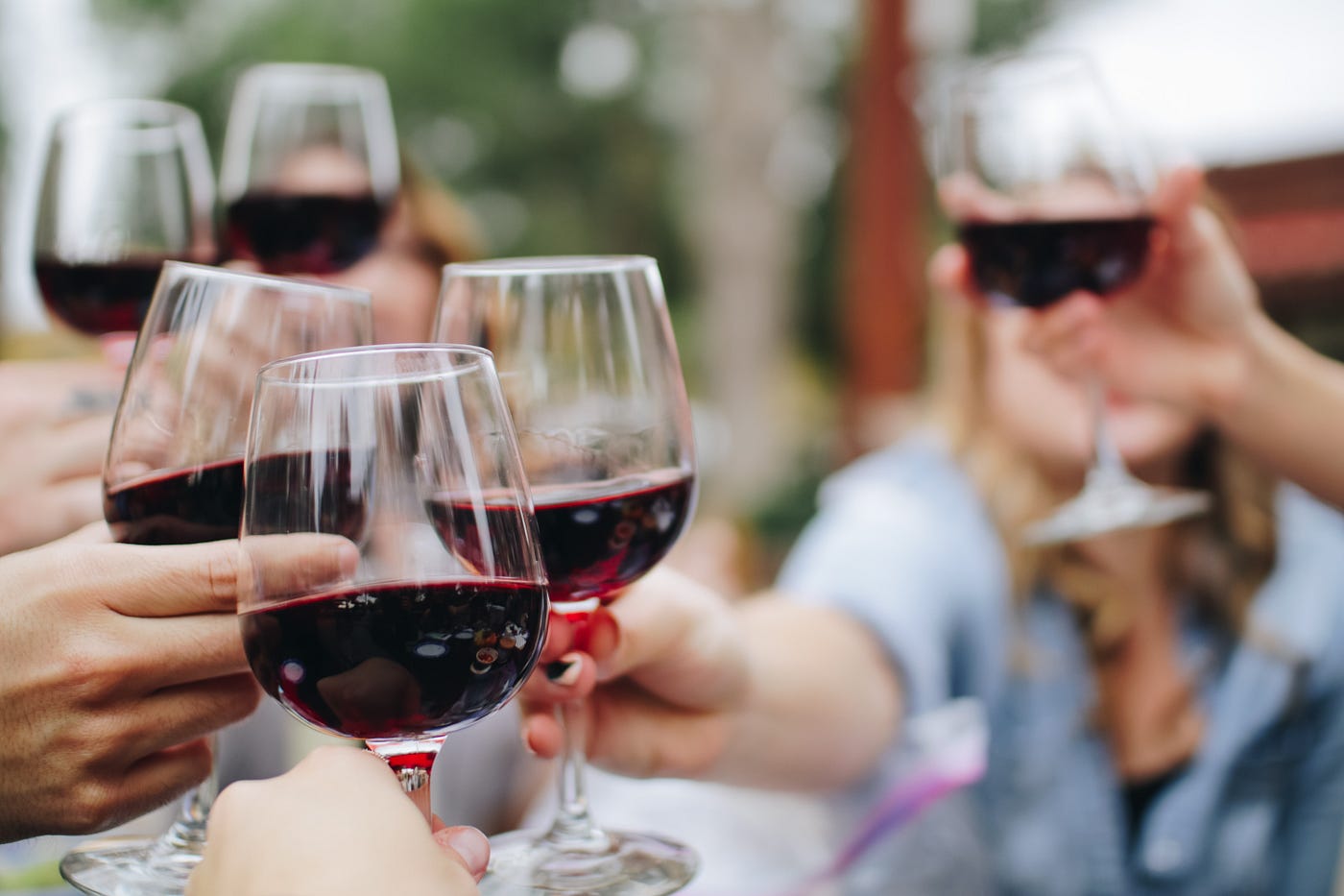Several hands raise glasses of white wine. We cannot see the individuals otherwise. Alcohol’s dehydrating effects can cause headaches. As you consume your glass of red wine, you may lose more fluids than you gain.